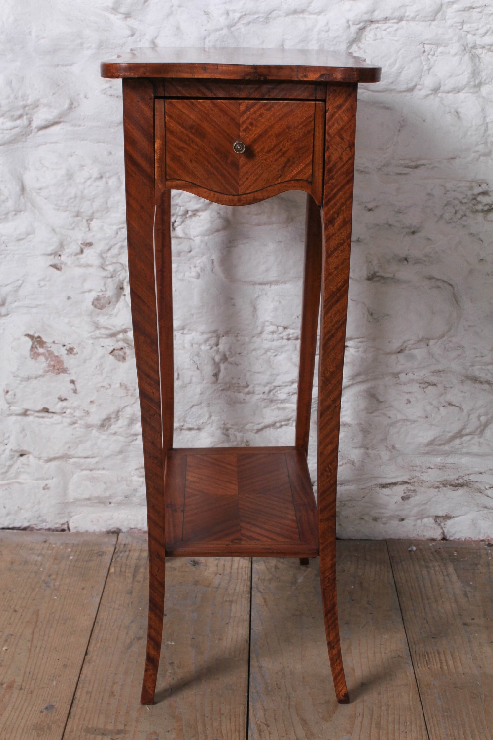 A tall French walnut veneer side table featuring a serpentine top with geometric parquetry inlay, a single front drawer, a lower tier shelf, and slender cabriole legs. View V