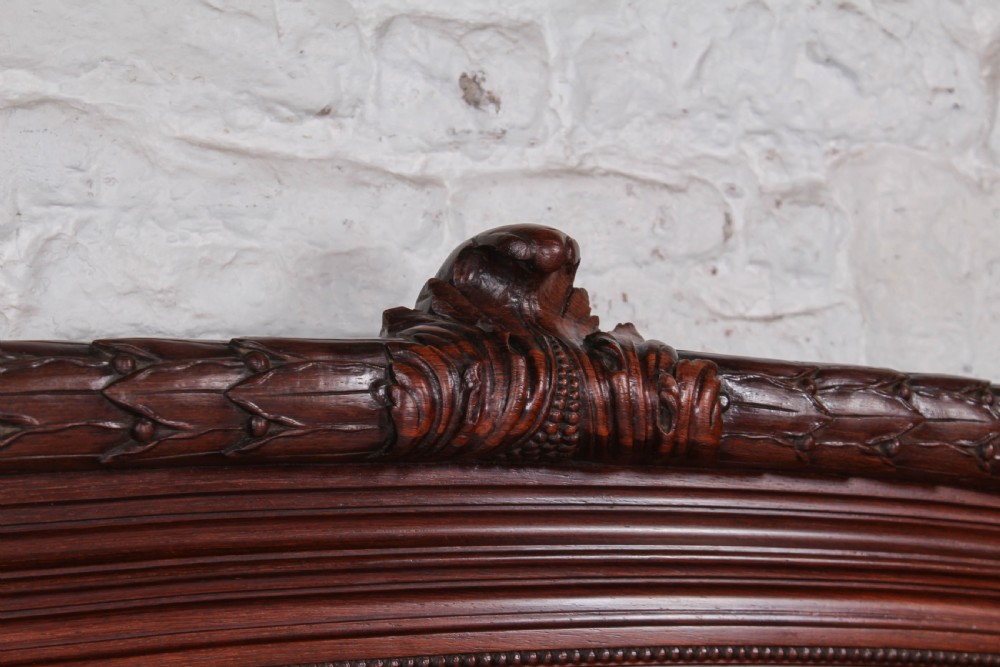 A French rosewood bed frame with a high arched headboard and a carved floral oval cartouche on the footboard. View V