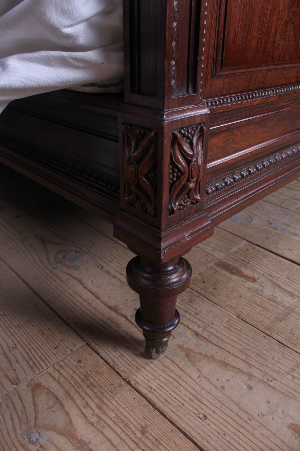 A French rosewood bed frame with a high arched headboard and a carved floral oval cartouche on the footboard. View VI