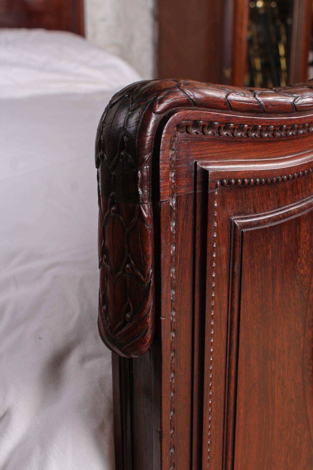 A French rosewood bed frame with a high arched headboard and a carved floral oval cartouche on the footboard. View VII