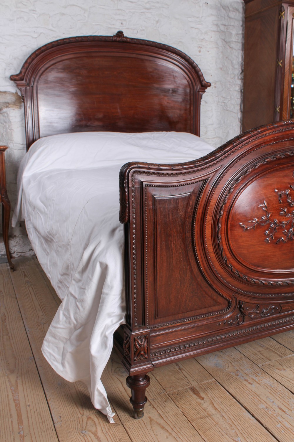 A French rosewood bed frame with a high arched headboard and a carved floral oval cartouche on the footboard. View IX