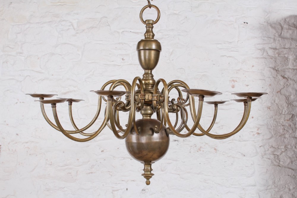 A Flemish style solid brass ceiling chandelier featuring multiple S-scrolled arms attached to a central turned baluster stem with a spherical base terminal.