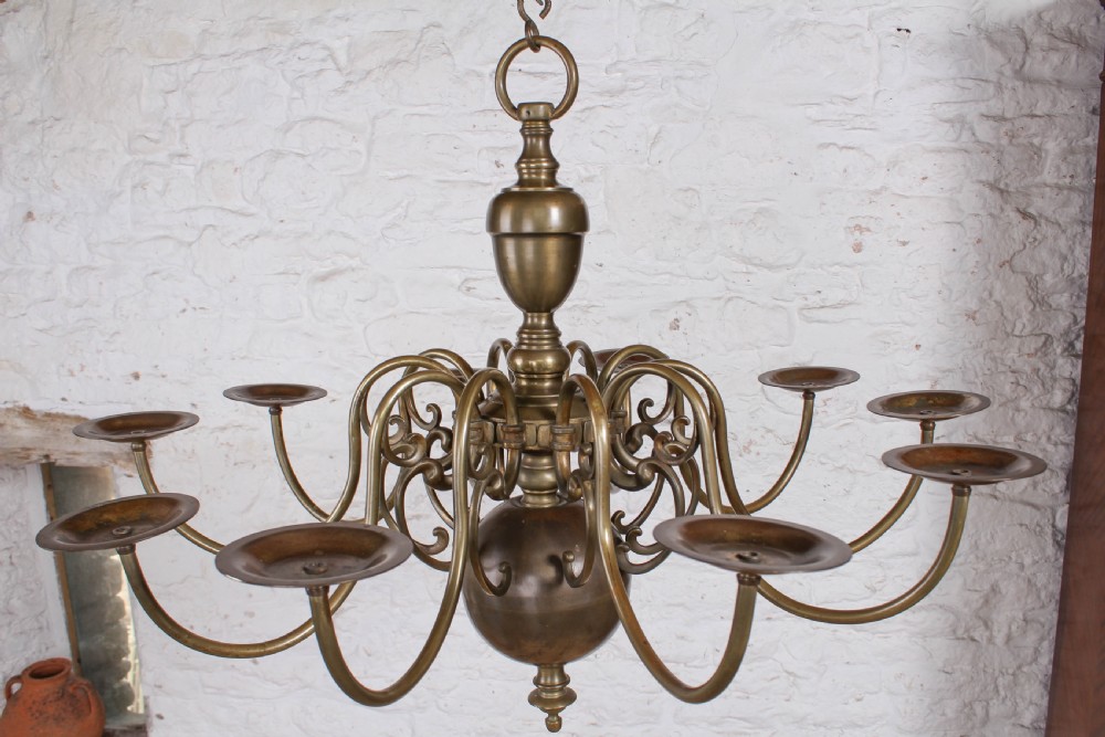 A Flemish style solid brass ceiling chandelier featuring multiple S-scrolled arms attached to a central turned baluster stem with a spherical base terminal. View II