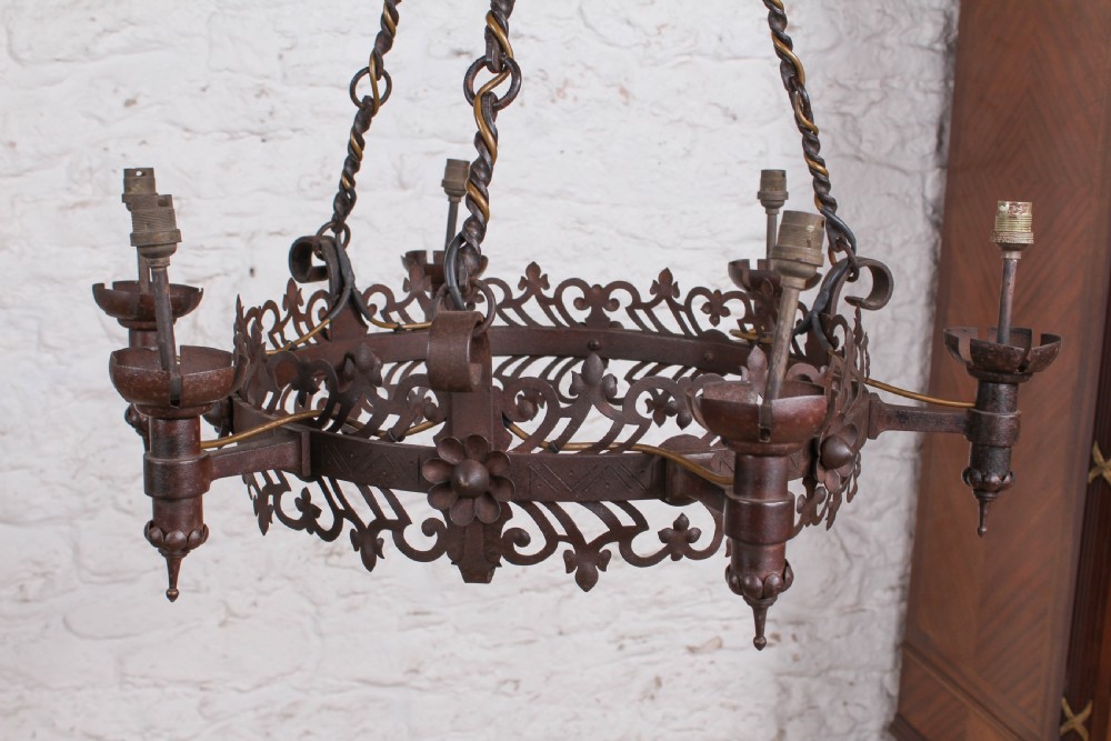 A French wrought iron chandelier with a pierced decorative rim, twisted iron support rods, and sculpted floral details. View III