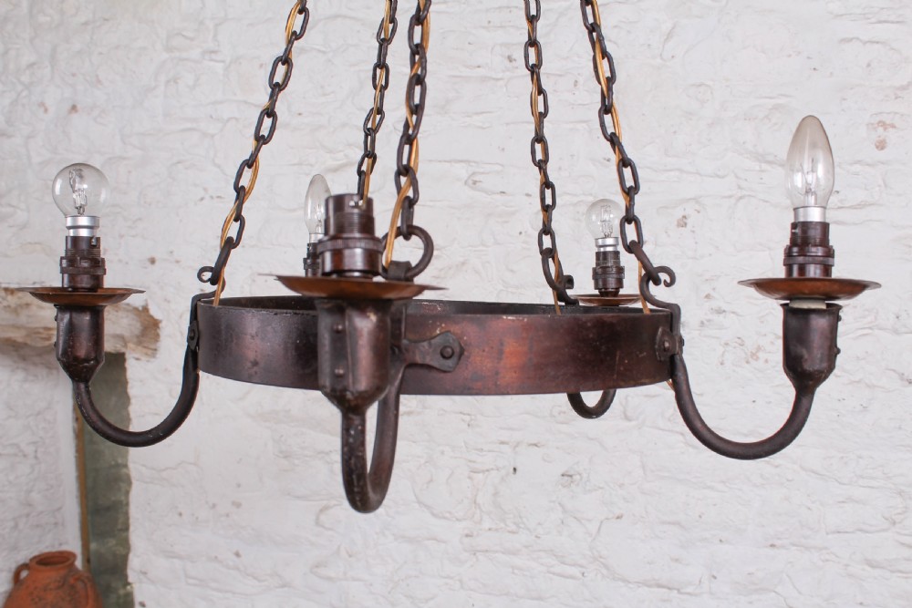 A patinated dark copper Arts and Crafts circular hoop chandelier suspended by four metal chains from a conical top cap. View II