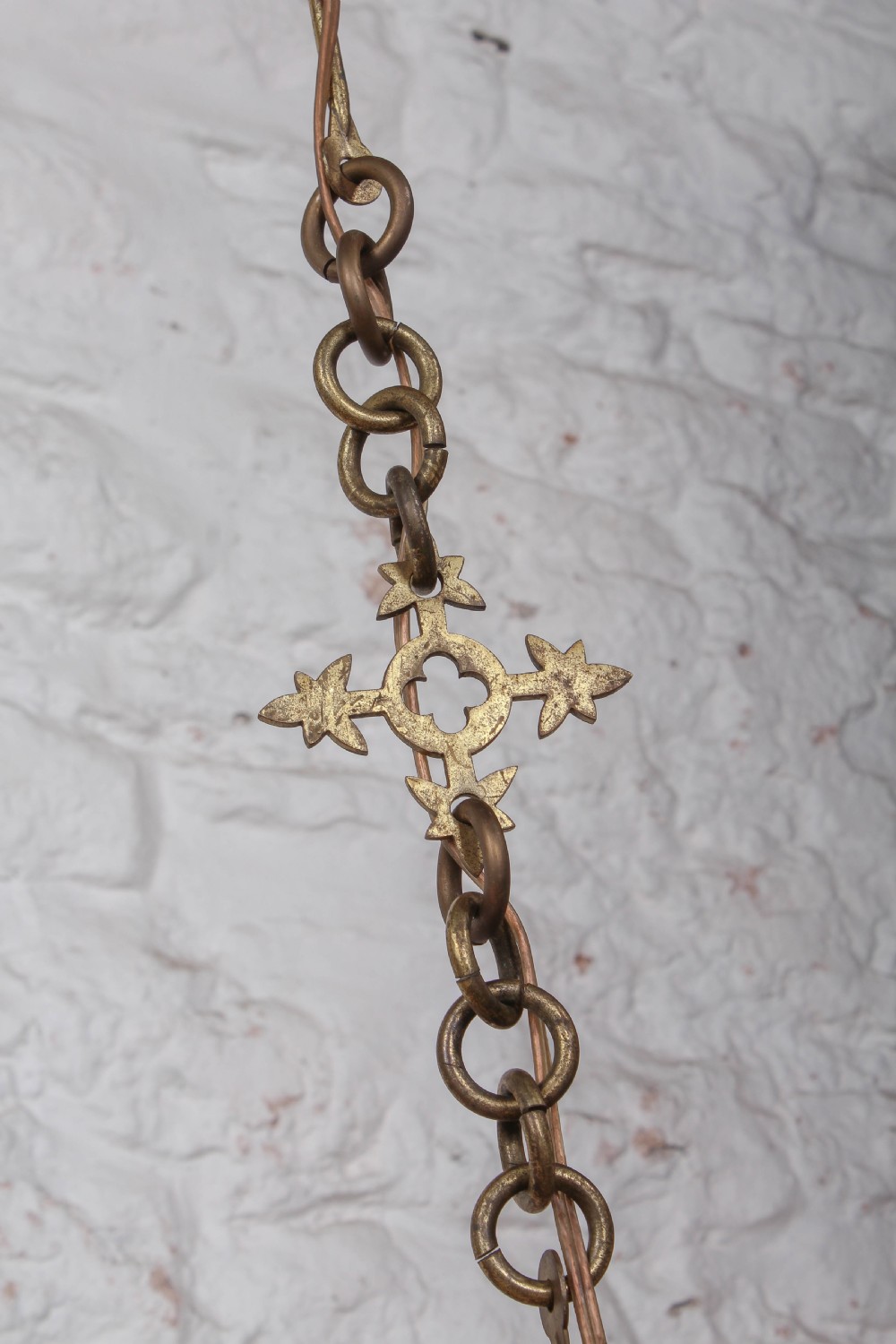 An Aesthetic Movement brass ecclesiastical corona chandelier featuring a circular band with painted Latin script, scalloped edges, multiple candle sconces, and hanging chains. View V