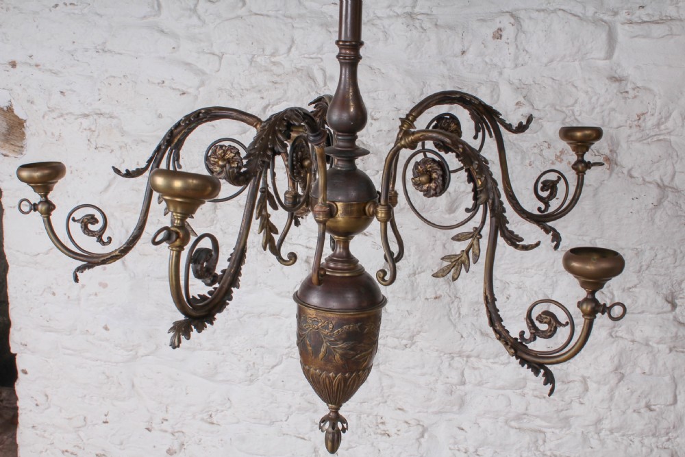 A French cast brass ceiling chandelier featuring scrolled arms, foliate leaves, floral rosettes, and a central turned stem with an urn-shaped lower finial. View II