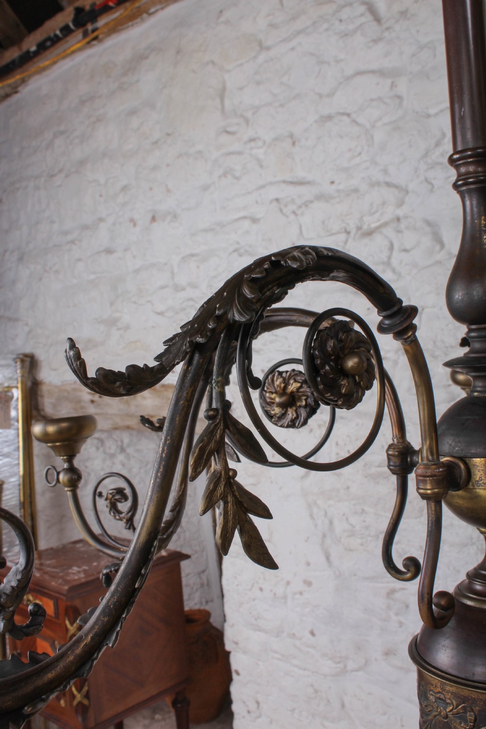 A French cast brass ceiling chandelier featuring scrolled arms, foliate leaves, floral rosettes, and a central turned stem with an urn-shaped lower finial. View III