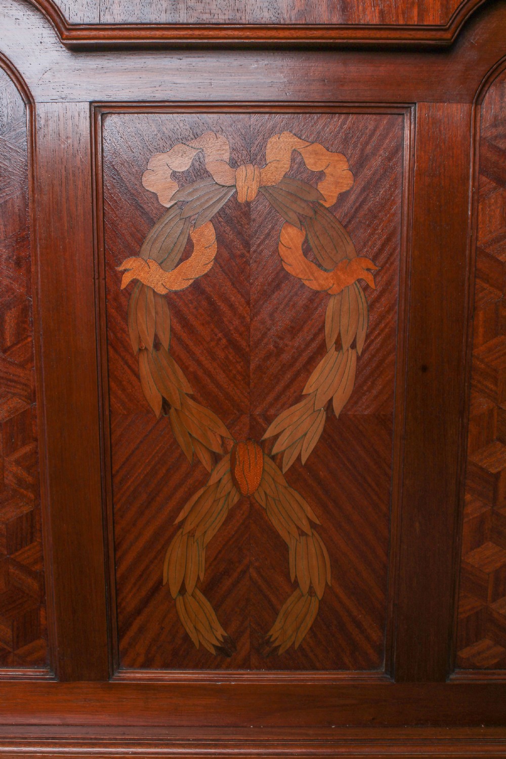 An antique French mahogany bed frame featuring geometric parquetry panels, fruitwood ribbon marquetry on the footboard, and gilt bronze mounts. View VII