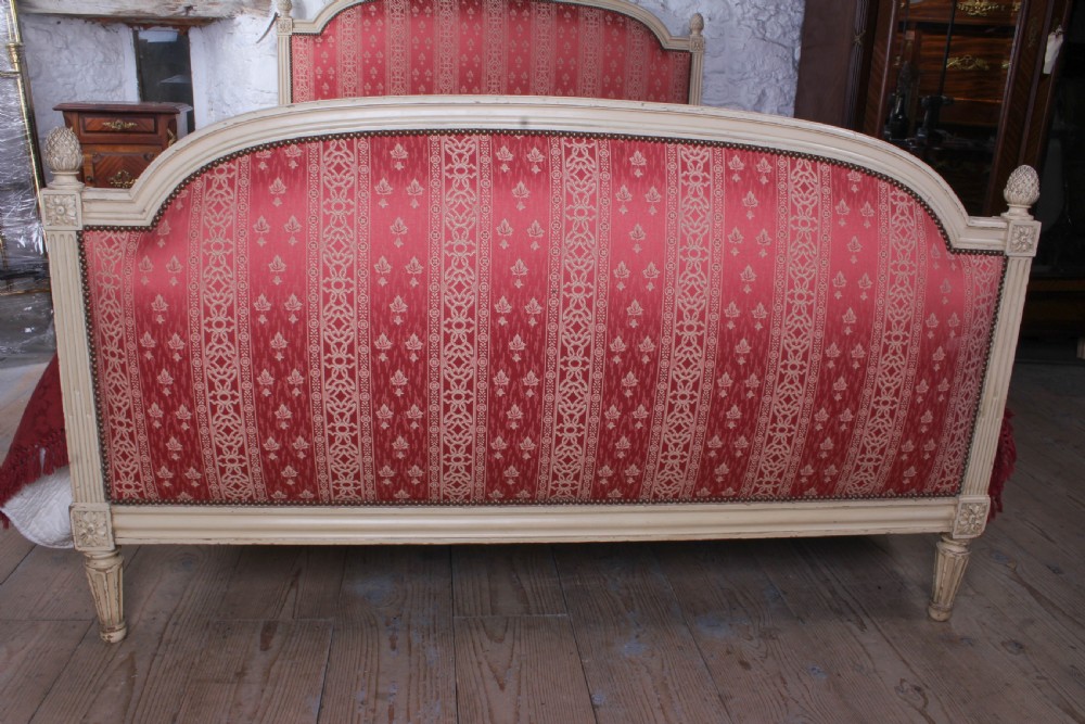 A French Louis XVI style king size bedstead featuring a cream painted carved timber frame and red patterned damask upholstered headboard and footboard. View V