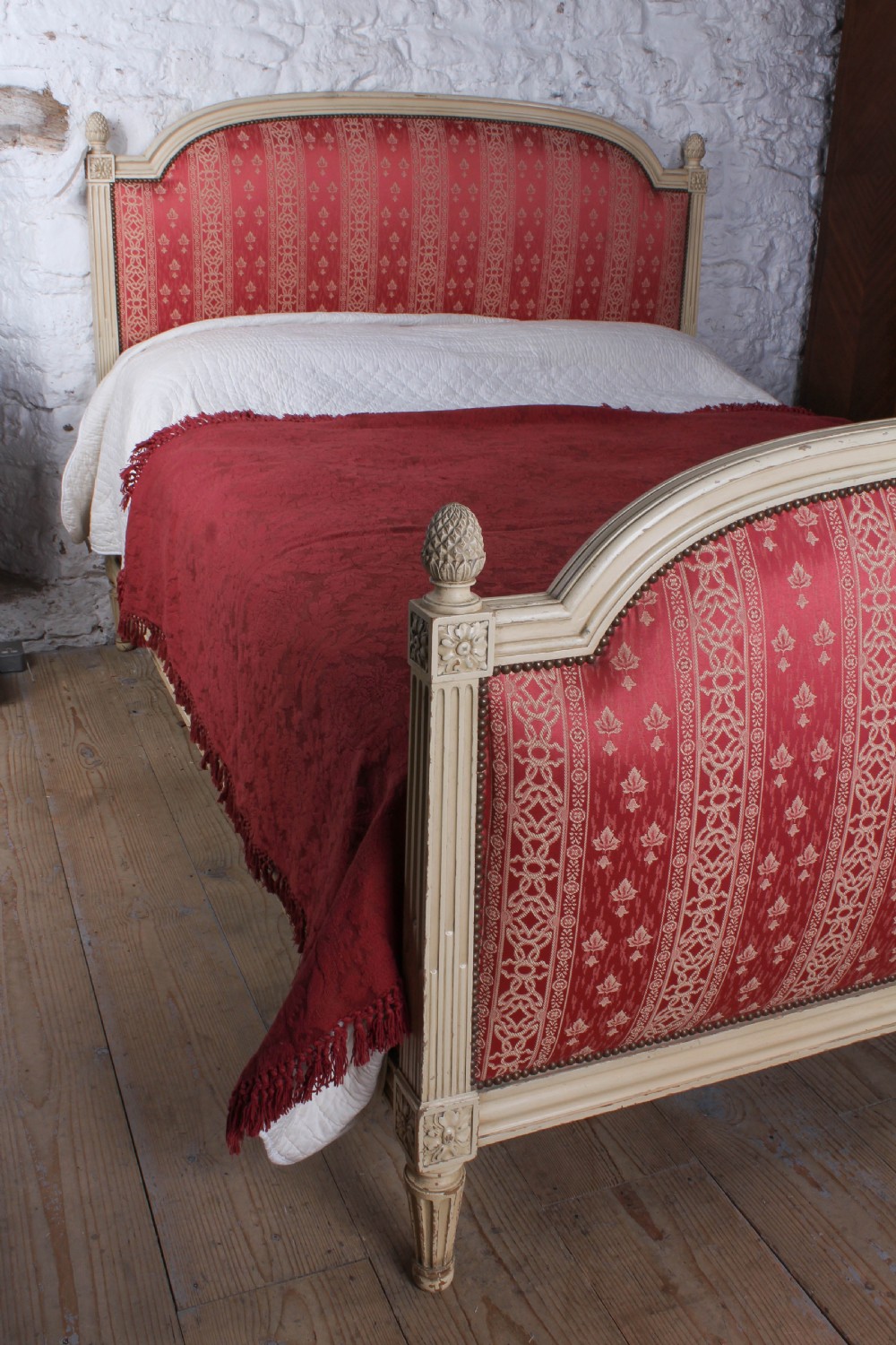 A French Louis XVI style king size bedstead featuring a cream painted carved timber frame and red patterned damask upholstered headboard and footboard. View VI