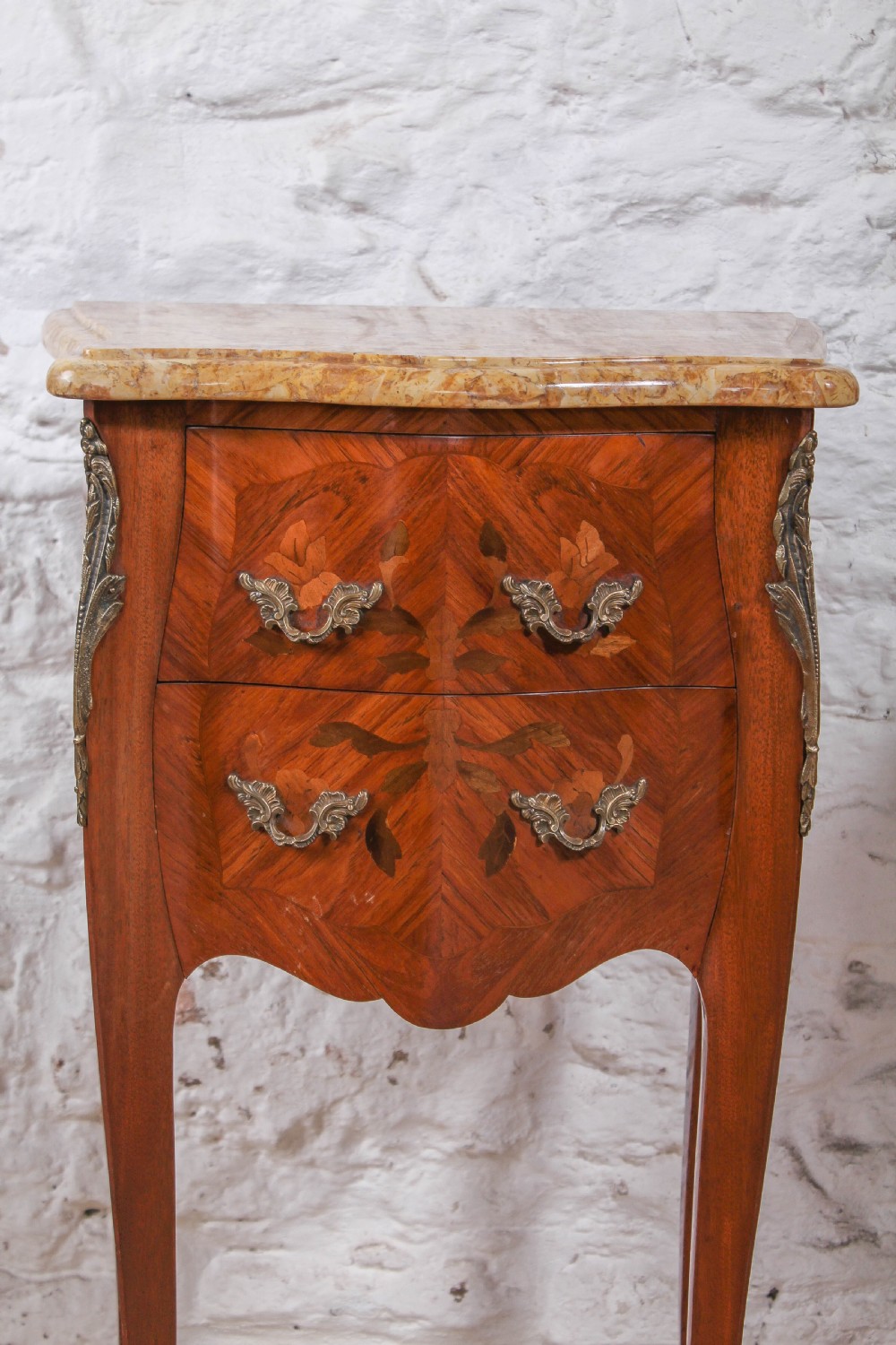 A pair of French Louis XV style bow-front bedside tables featuring floral marquetry inlay, cabriole legs, brass handles, and marble tops. View II