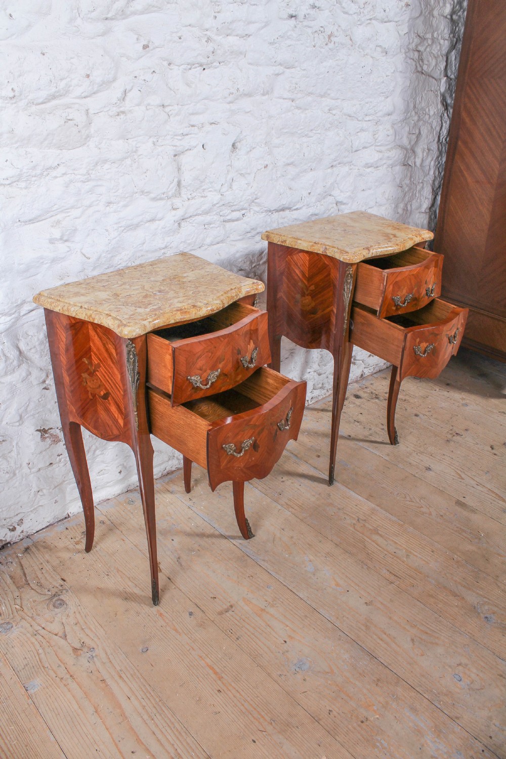 A pair of French Louis XV style bow-front bedside tables featuring floral marquetry inlay, cabriole legs, brass handles, and marble tops. View IV