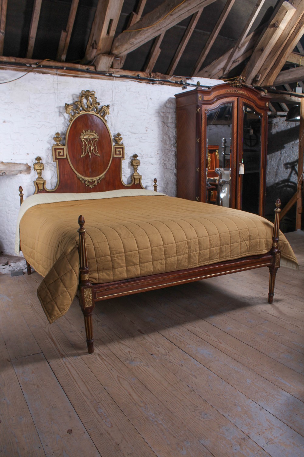 An antique mahogany super king bed featuring a high headboard with an oval central medallion, carved giltwood crest, Greek key motifs, and turned posts. View IX