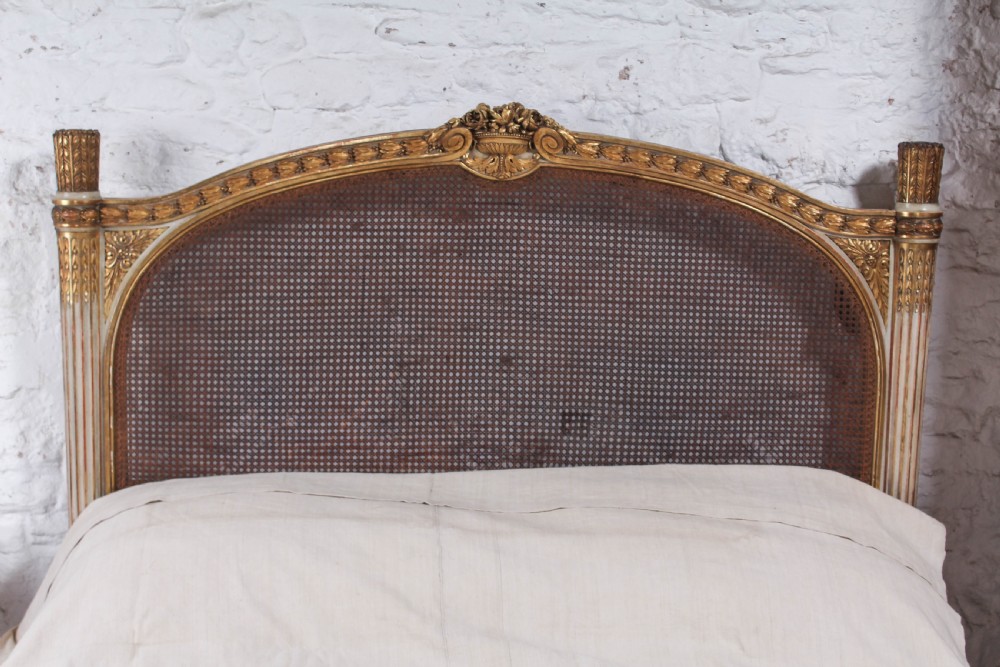 A Louis XVI style French corbeille bed featuring a carved giltwood frame, woven cane panels, fluted legs, and a rounded footboard. View II