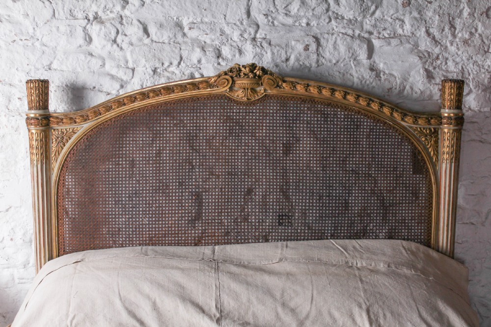A Louis XVI style French corbeille bed featuring a carved giltwood frame, woven cane panels, fluted legs, and a rounded footboard. View III
