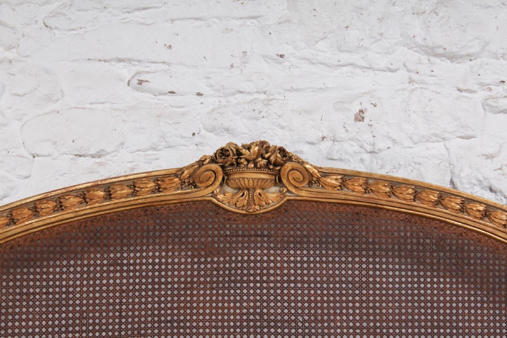 A Louis XVI style French corbeille bed featuring a carved giltwood frame, woven cane panels, fluted legs, and a rounded footboard. View IX