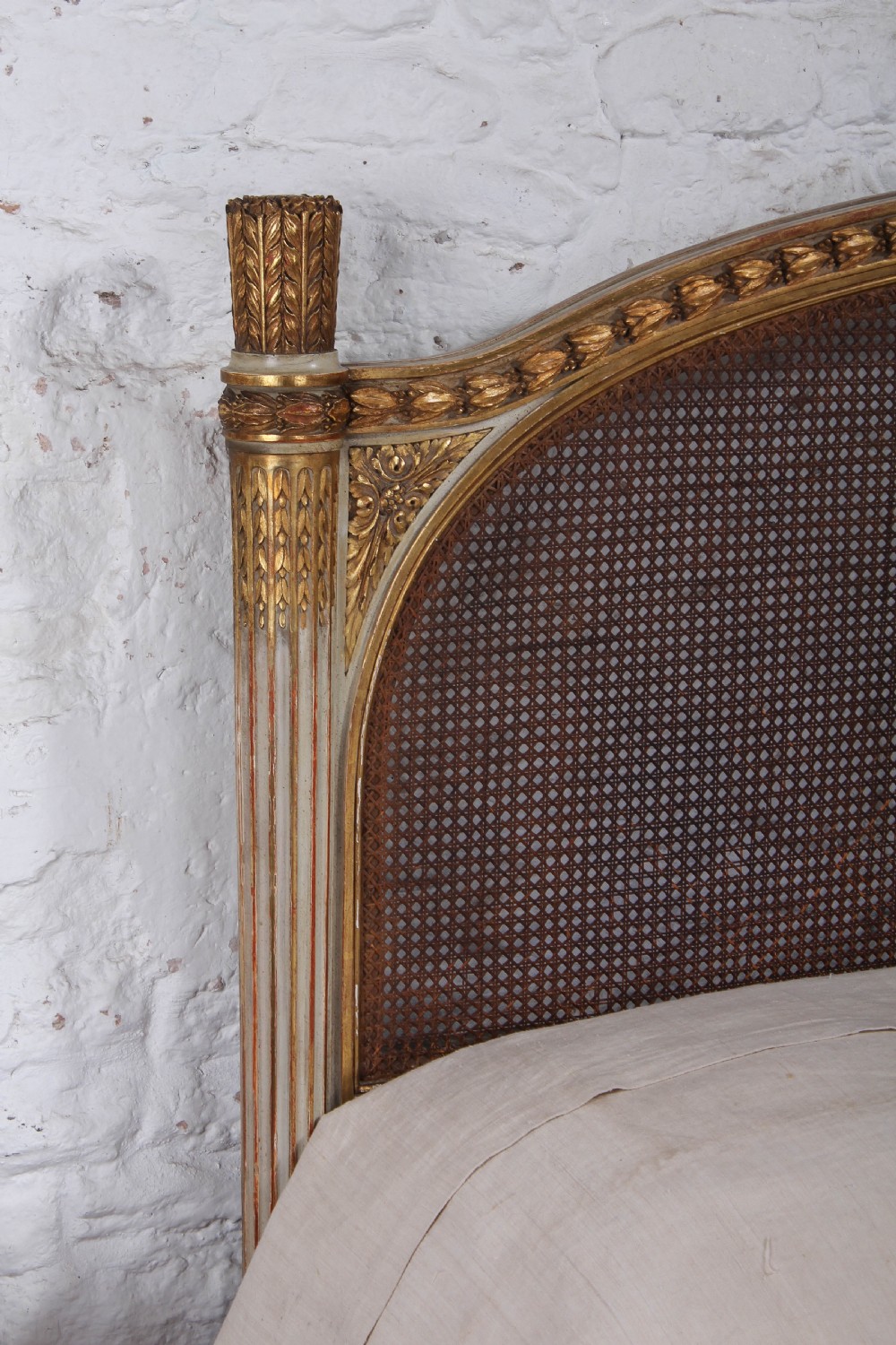 A Louis XVI style French corbeille bed featuring a carved giltwood frame, woven cane panels, fluted legs, and a rounded footboard. View X