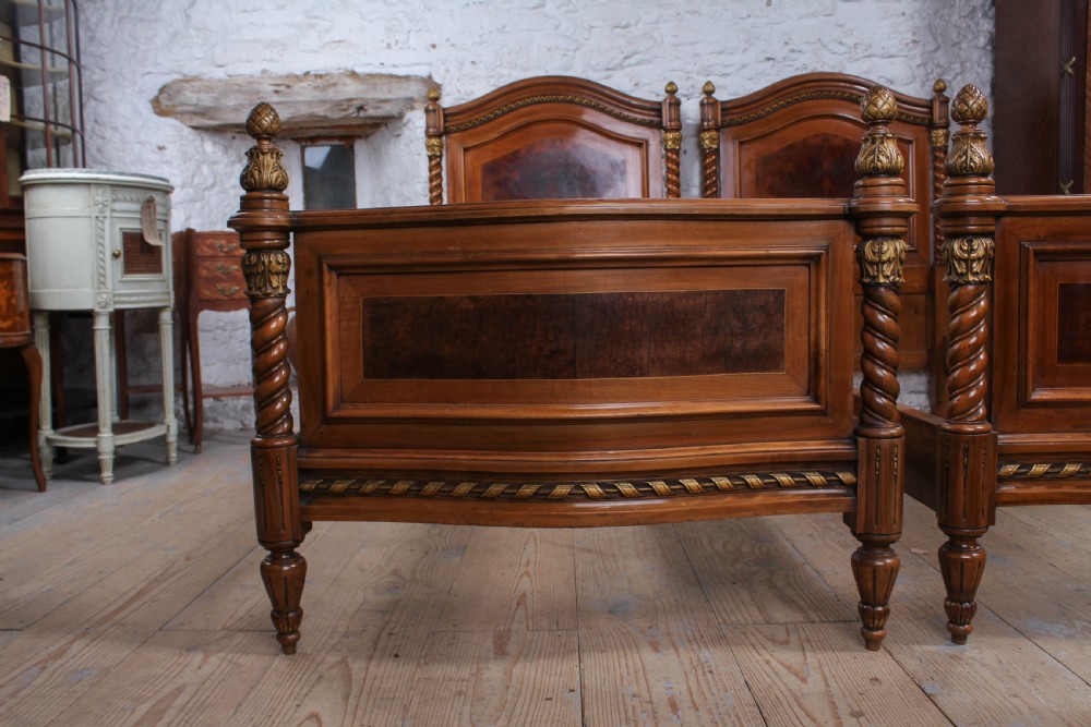 A pair of matching continental mahogany single beds featuring arched headboards, flame veneer panels, spiral turned posts, and gilt pineapple finials. View III