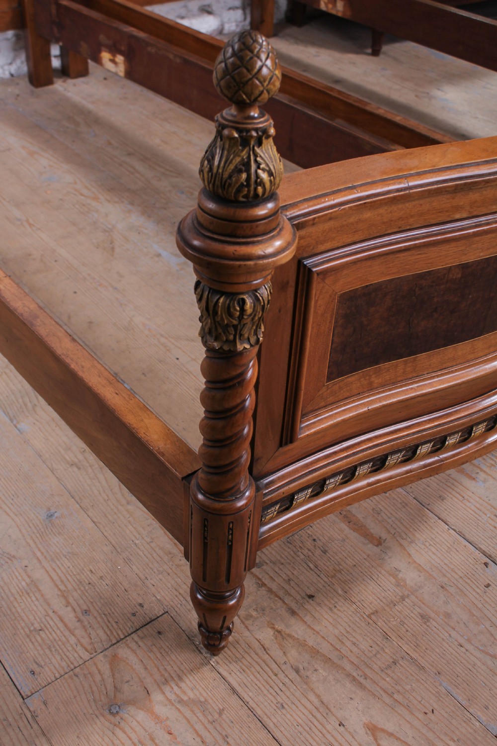 A pair of matching continental mahogany single beds featuring arched headboards, flame veneer panels, spiral turned posts, and gilt pineapple finials. View V