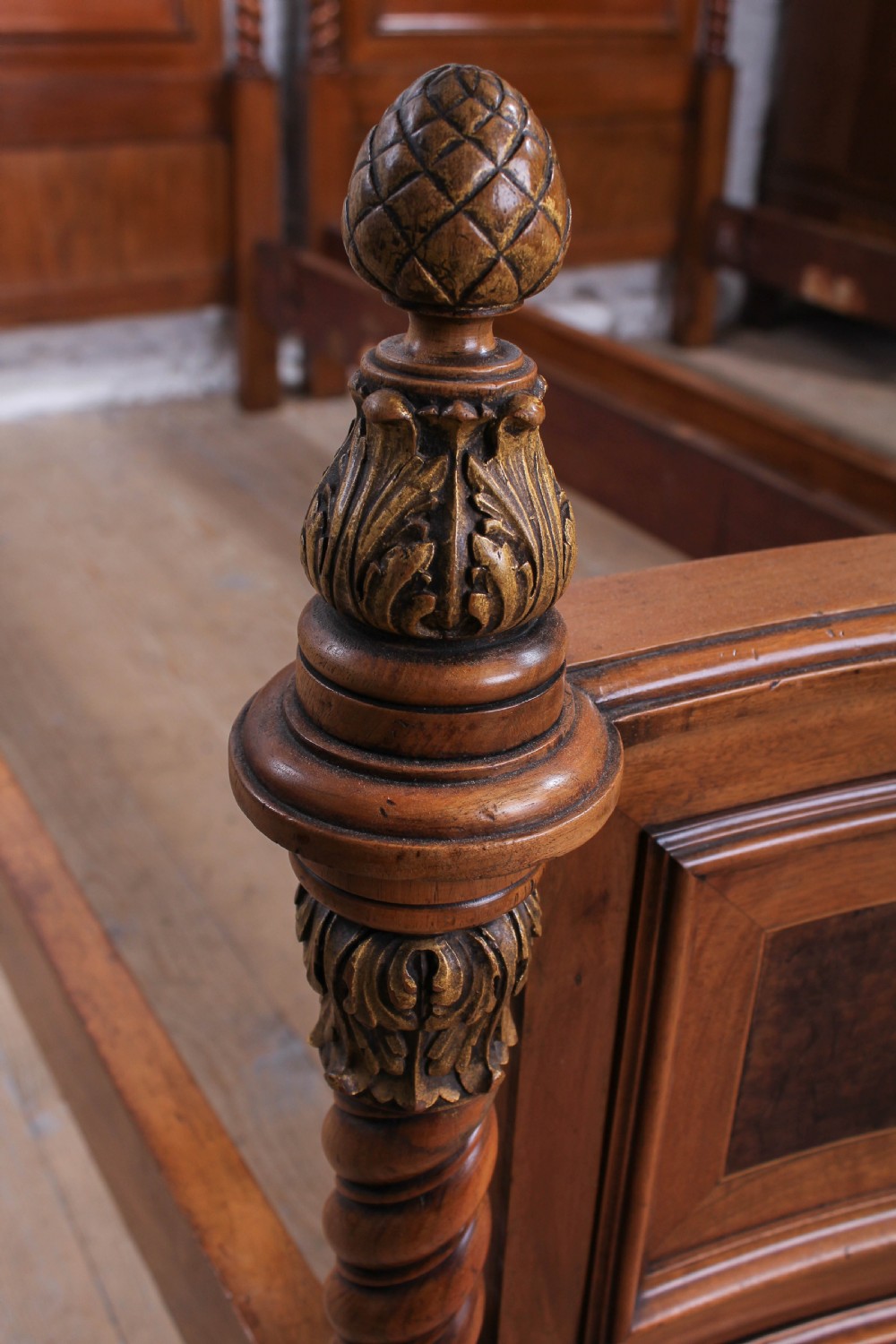 A pair of matching continental mahogany single beds featuring arched headboards, flame veneer panels, spiral turned posts, and gilt pineapple finials. View VI