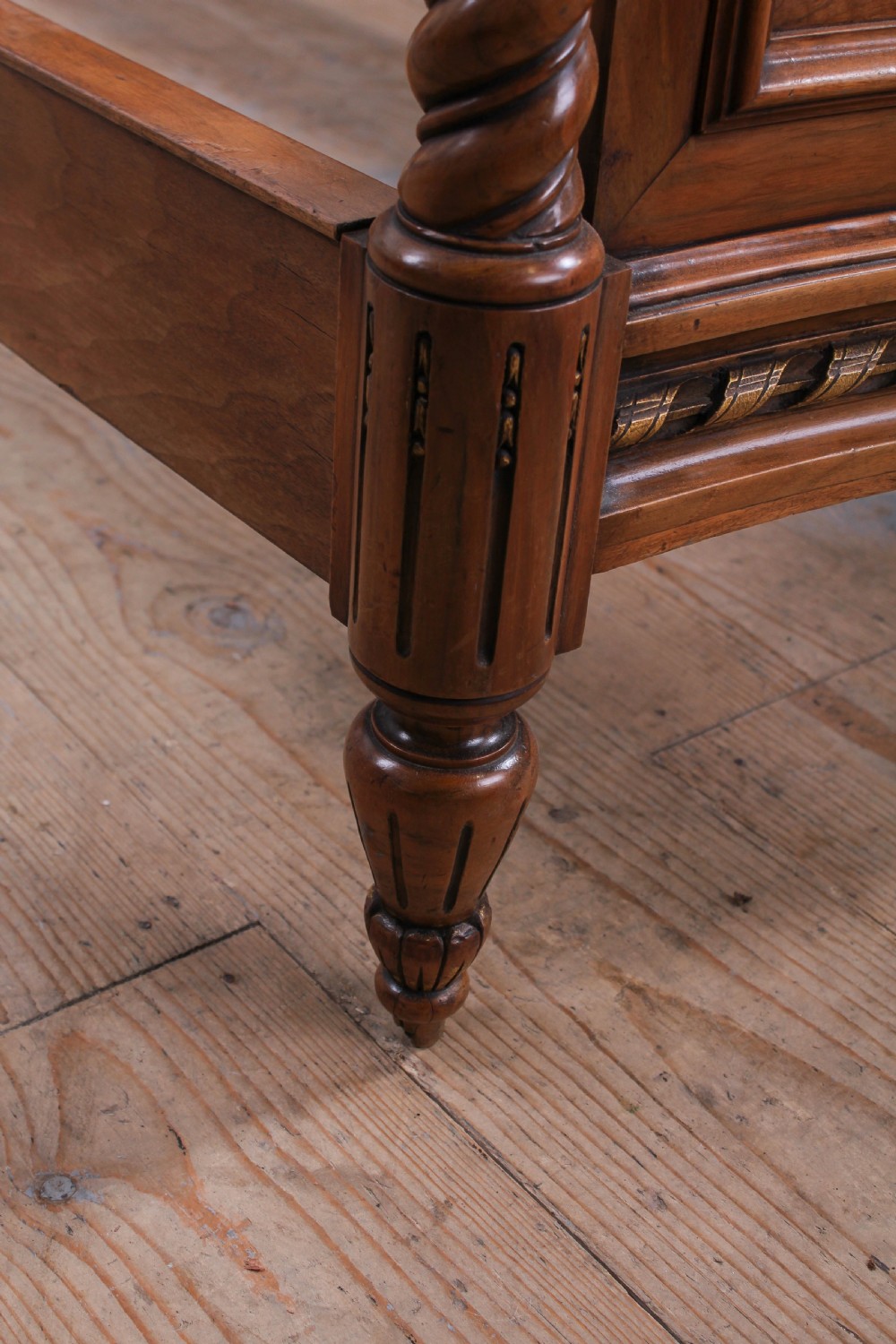 A pair of matching continental mahogany single beds featuring arched headboards, flame veneer panels, spiral turned posts, and gilt pineapple finials. View VII