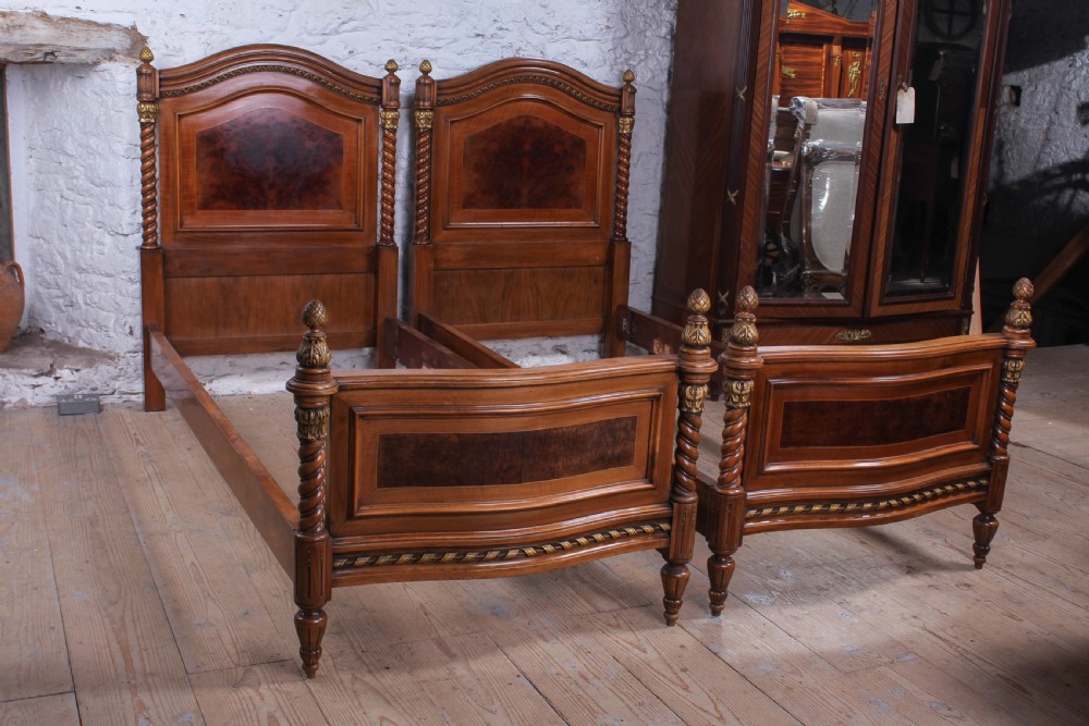 A pair of matching continental mahogany single beds featuring arched headboards, flame veneer panels, spiral turned posts, and gilt pineapple finials. View VIII