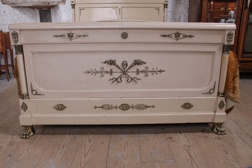 An off-white painted French king-size bedstead featuring gilt metal mounts, torch motifs, and carved claw feet. View V