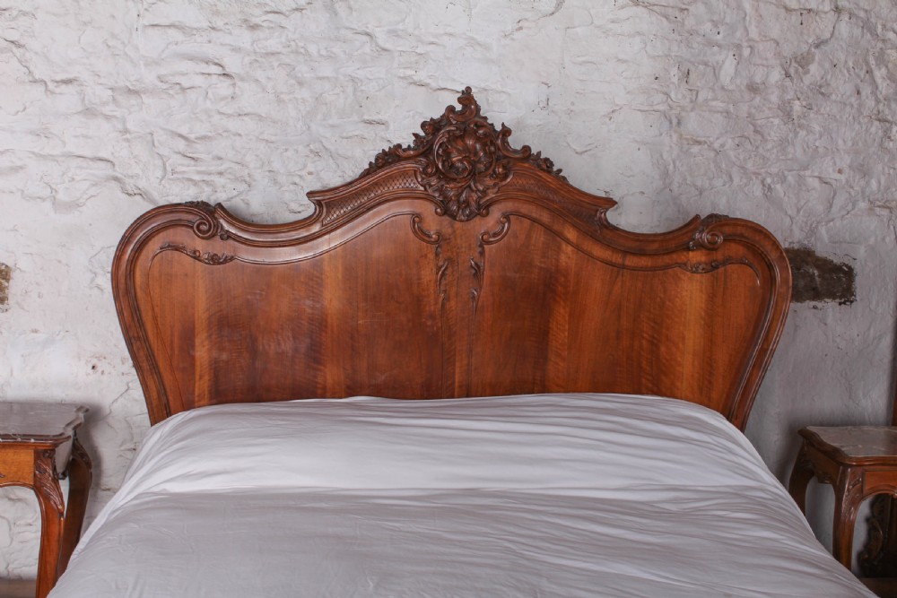 A French Louis XV style carved timber bedroom suite featuring a king-size bedstead, matching bedside cabinet, and three-door mirrored armoire. View II