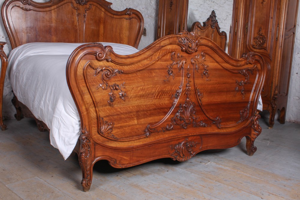 A French Louis XV style carved timber bedroom suite featuring a king-size bedstead, matching bedside cabinet, and three-door mirrored armoire. View III