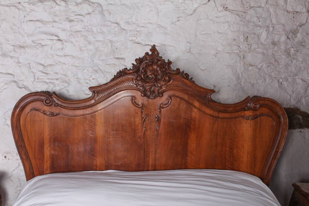 A French Louis XV style carved timber bedroom suite featuring a king-size bedstead, matching bedside cabinet, and three-door mirrored armoire. View IV