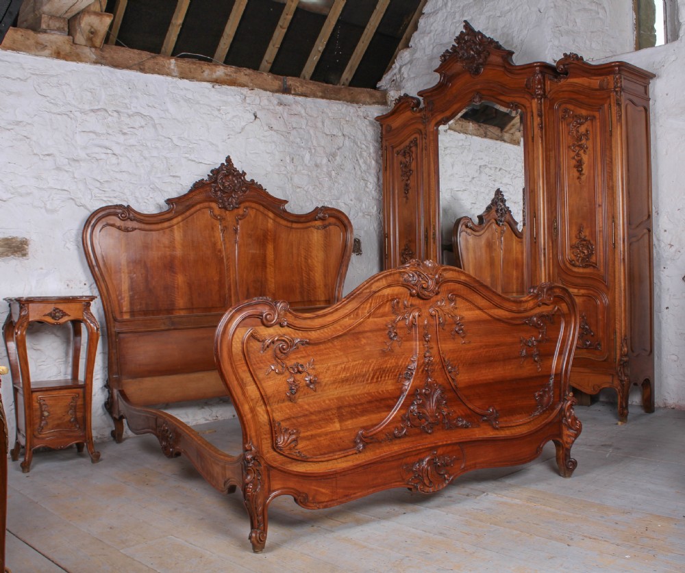A French Louis XV style carved timber bedroom suite featuring a king-size bedstead, matching bedside cabinet, and three-door mirrored armoire. View IX