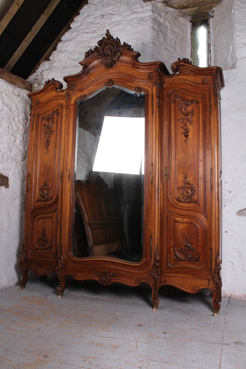 A French Louis XV style carved timber bedroom suite featuring a king-size bedstead, matching bedside cabinet, and three-door mirrored armoire. View X