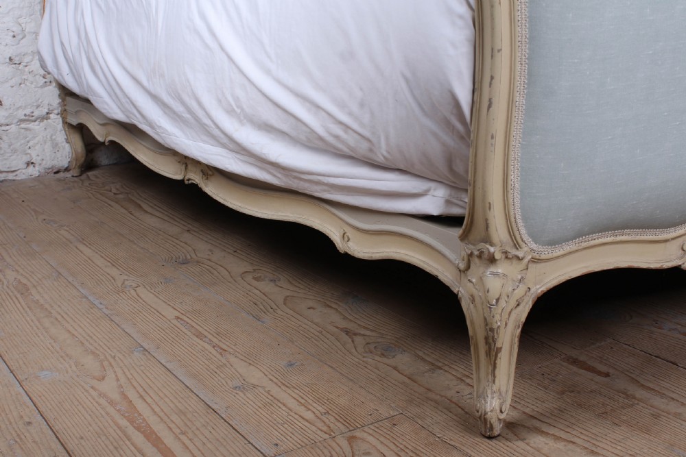 A Louis XV style king-size bed frame featuring a carved cream painted timber surround, upholstered headboard and footboard in pale blue fabric, resting on cabriole legs. View III