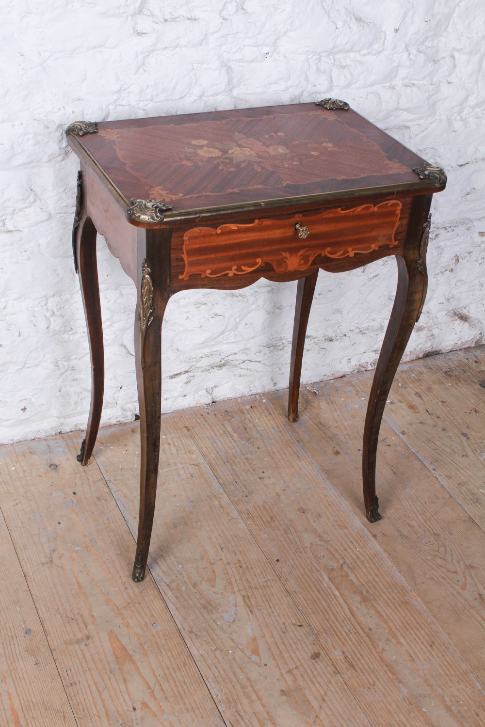 A French Louis XV style walnut side table featuring floral marquetry inlay, cabriole legs, and brass ormolu mounts.