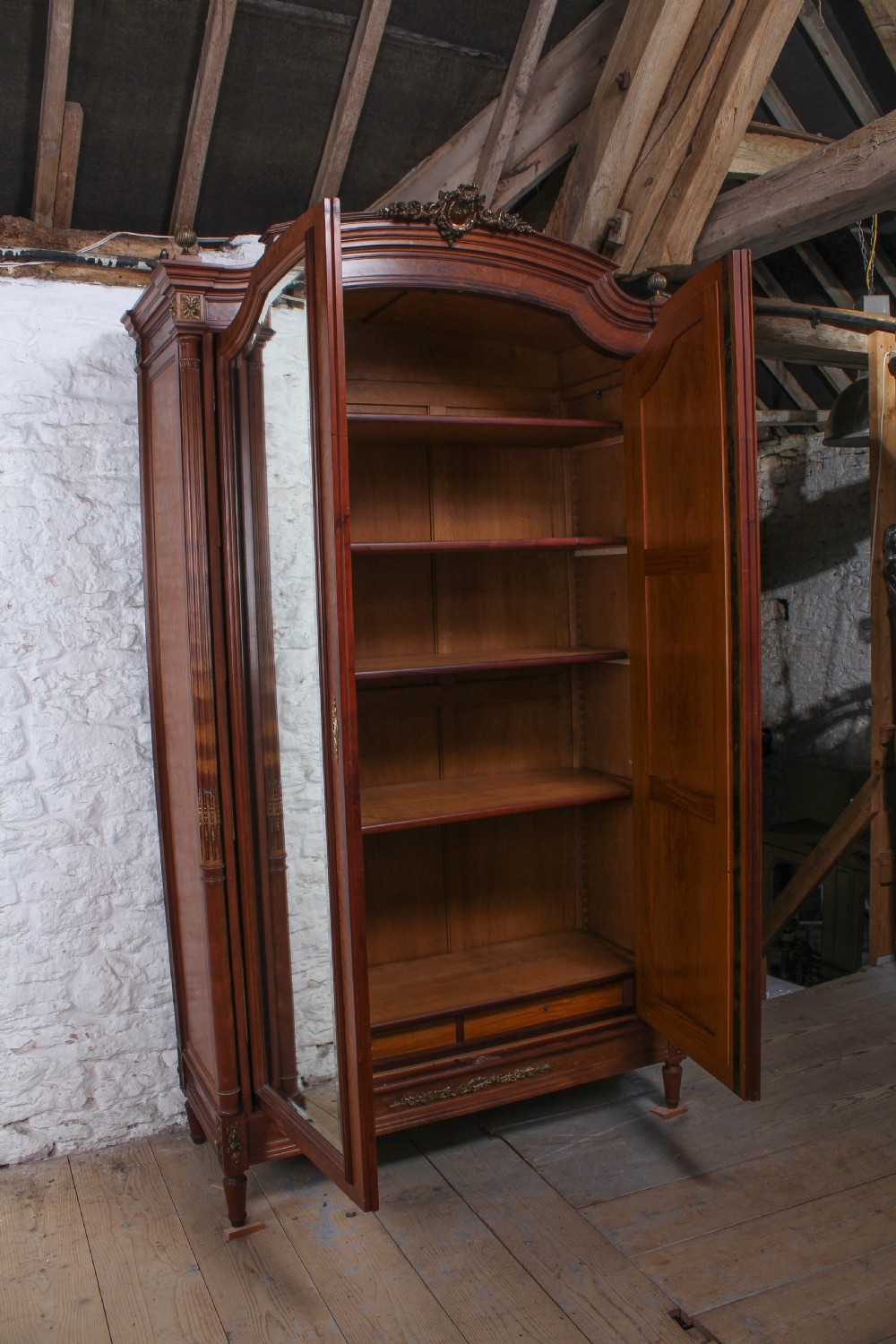 A tall French Louis XVI Revival warm brown wood armoire featuring arched twin mirrored doors, parquetry side panels, and decorative brass mounts. View III