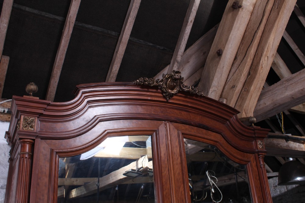 A tall French Louis XVI Revival warm brown wood armoire featuring arched twin mirrored doors, parquetry side panels, and decorative brass mounts. View VI