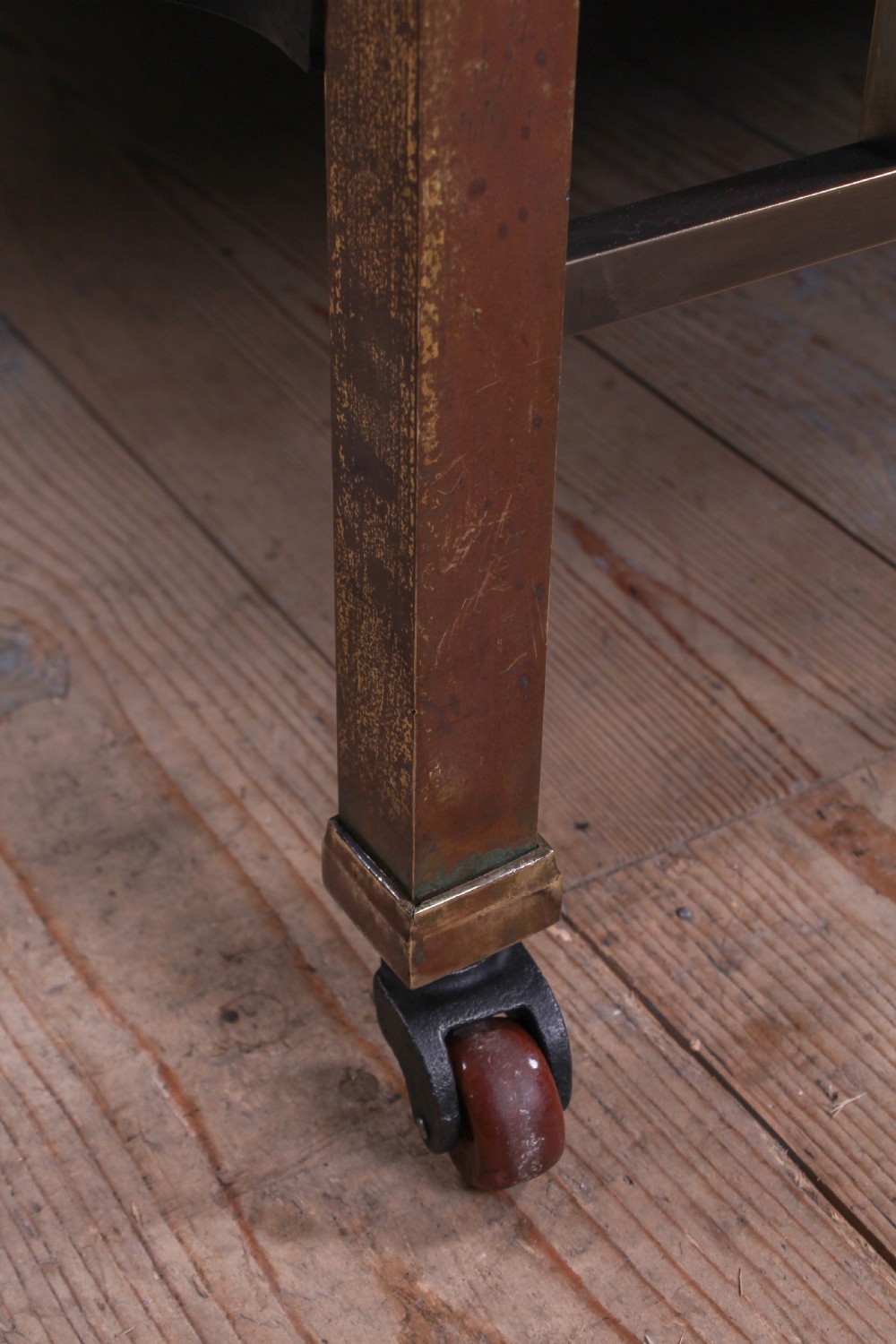 An antique Victorian king-size bed frame featuring vertical brass spindles, square corner posts, and an aged metallic patina set on castors. View III