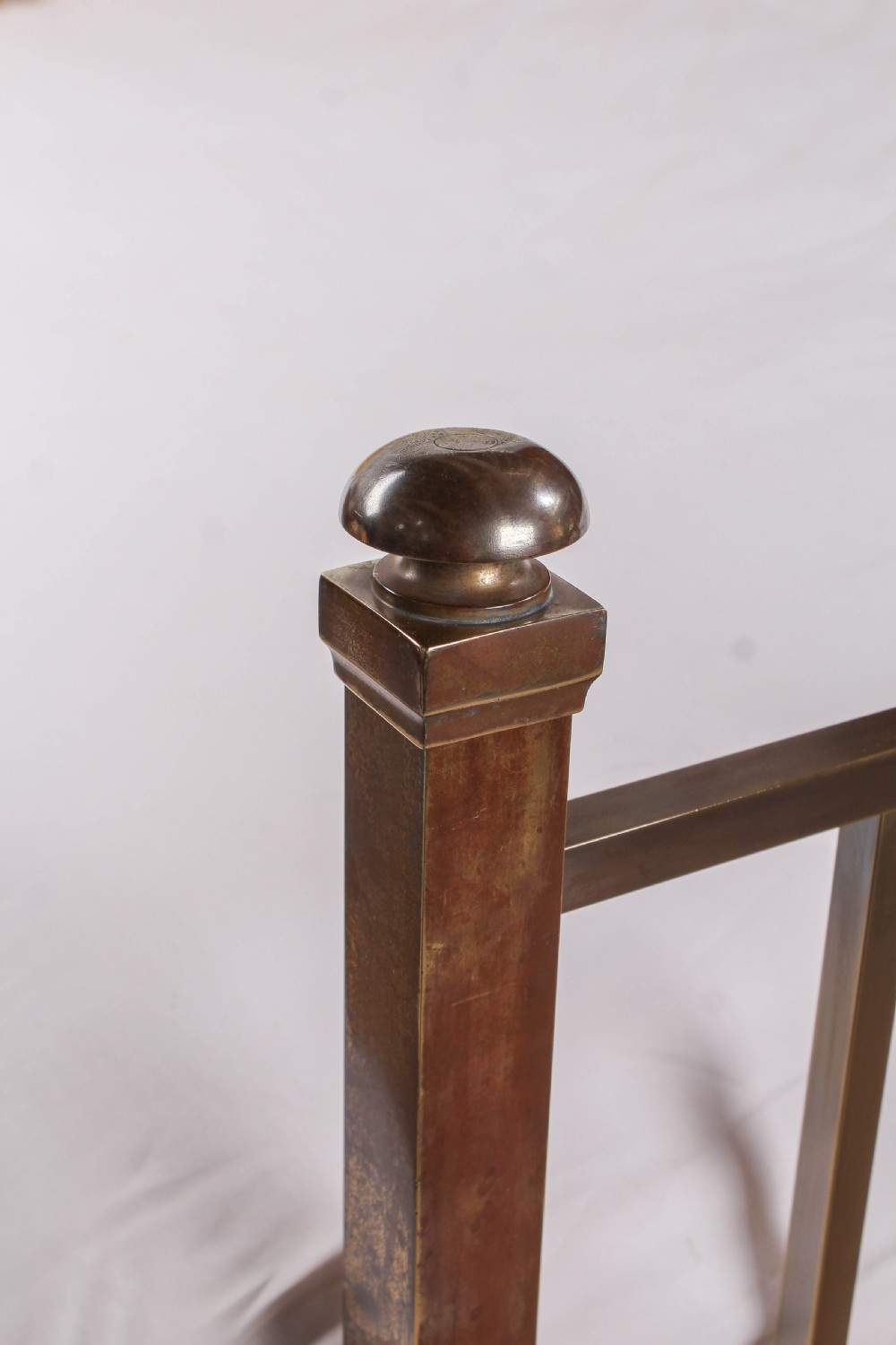 An antique Victorian king-size bed frame featuring vertical brass spindles, square corner posts, and an aged metallic patina set on castors. View IV