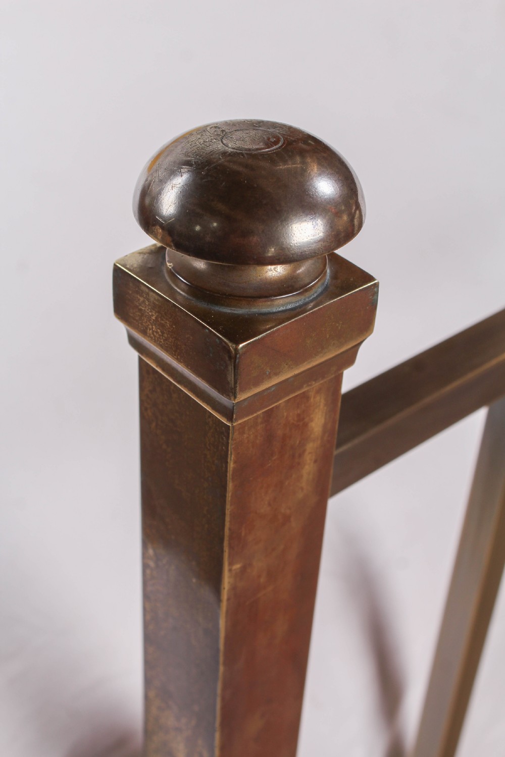 An antique Victorian king-size bed frame featuring vertical brass spindles, square corner posts, and an aged metallic patina set on castors. View VII