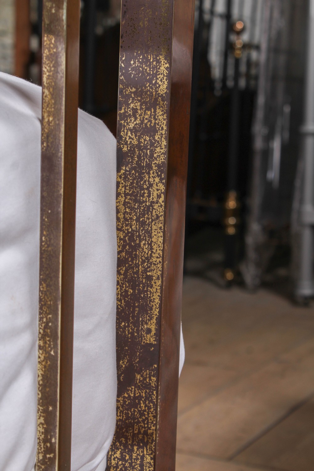 An antique Victorian king-size bed frame featuring vertical brass spindles, square corner posts, and an aged metallic patina set on castors. View VIII