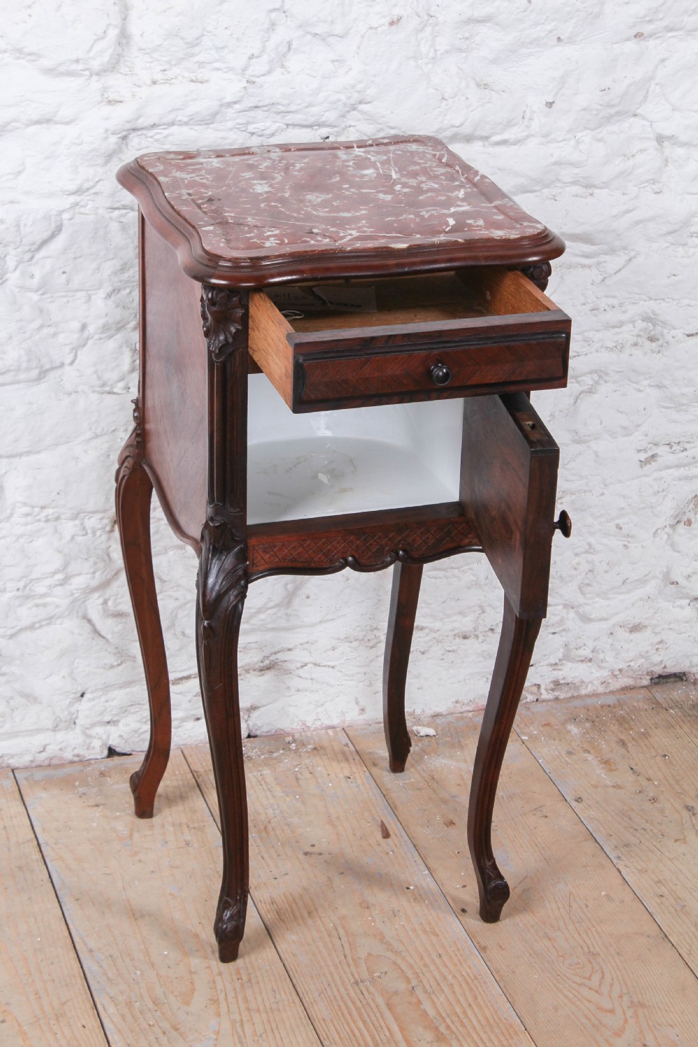 A dark wood Louis XV style bedside cabinet featuring an inset marble top, quarter-veneered door, drawer, carved apron, and tall cabriole legs. View II