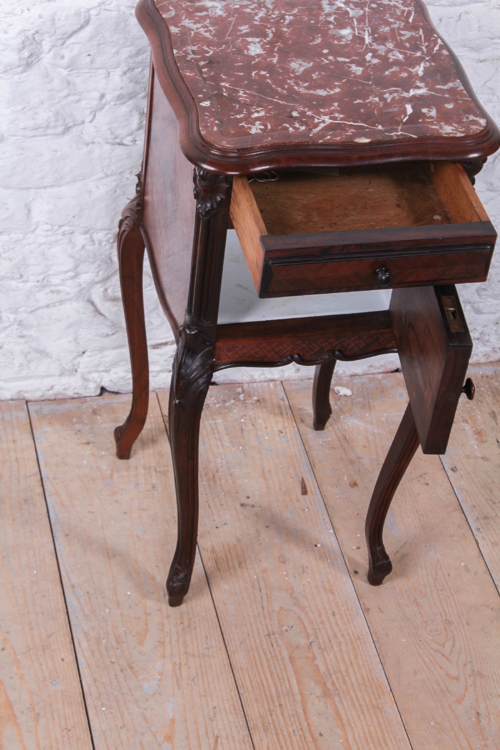 A dark wood Louis XV style bedside cabinet featuring an inset marble top, quarter-veneered door, drawer, carved apron, and tall cabriole legs. View III