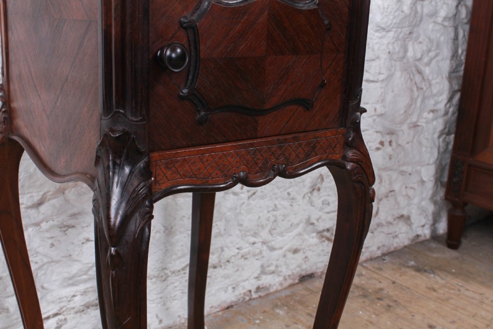 A dark wood Louis XV style bedside cabinet featuring an inset marble top, quarter-veneered door, drawer, carved apron, and tall cabriole legs. View VI