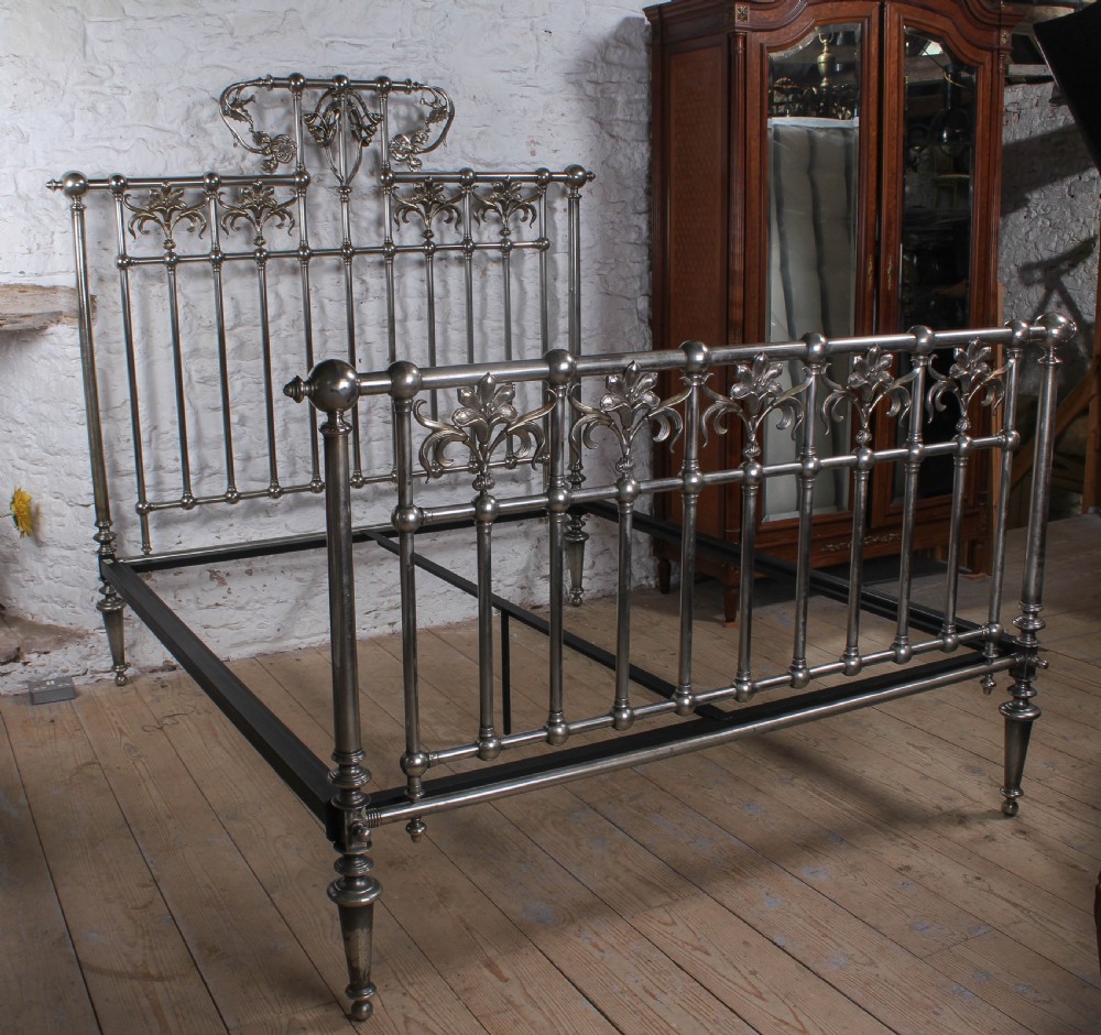 A nickel-plated super king size bedstead featuring Art Nouveau floral metalwork detailing on the arched headboard and footboard. View II
