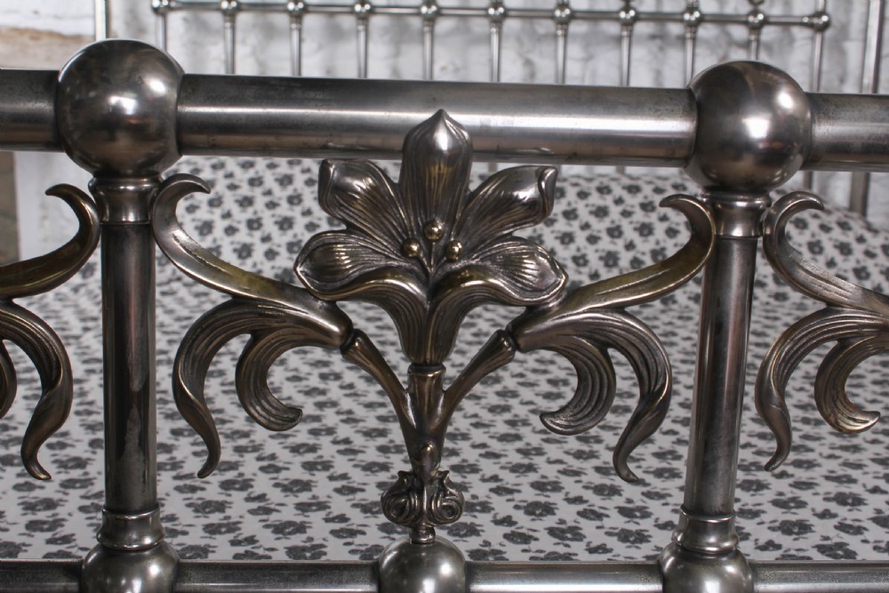 A nickel-plated super king size bedstead featuring Art Nouveau floral metalwork detailing on the arched headboard and footboard. View IV