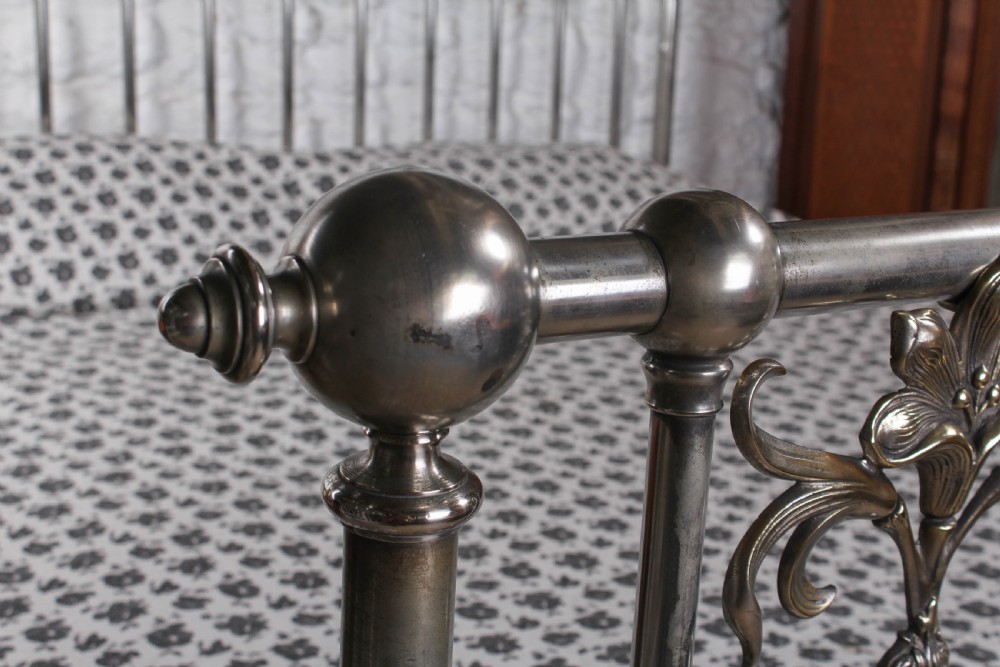 A nickel-plated super king size bedstead featuring Art Nouveau floral metalwork detailing on the arched headboard and footboard. View V