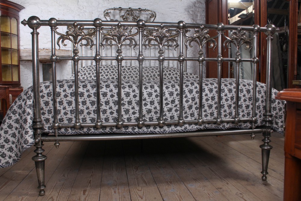 A nickel-plated super king size bedstead featuring Art Nouveau floral metalwork detailing on the arched headboard and footboard. View VIII