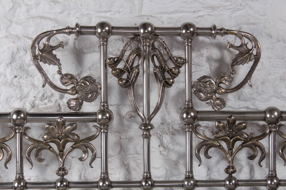 A nickel-plated super king size bedstead featuring Art Nouveau floral metalwork detailing on the arched headboard and footboard. View IX