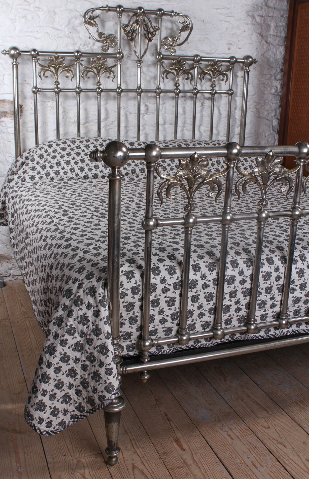 A nickel-plated super king size bedstead featuring Art Nouveau floral metalwork detailing on the arched headboard and footboard. View X